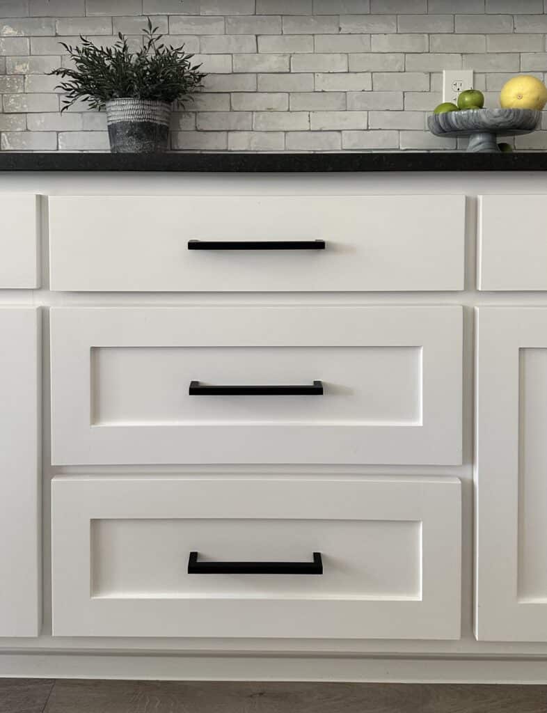 white shaker style kitchen cabinets with black countertop and matte black bar pulls