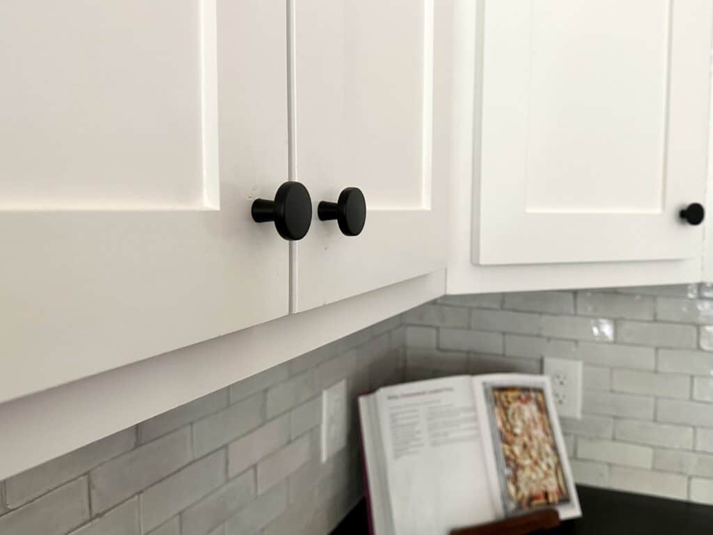 matte black knobs on white shaker style upper kitchen cabinets